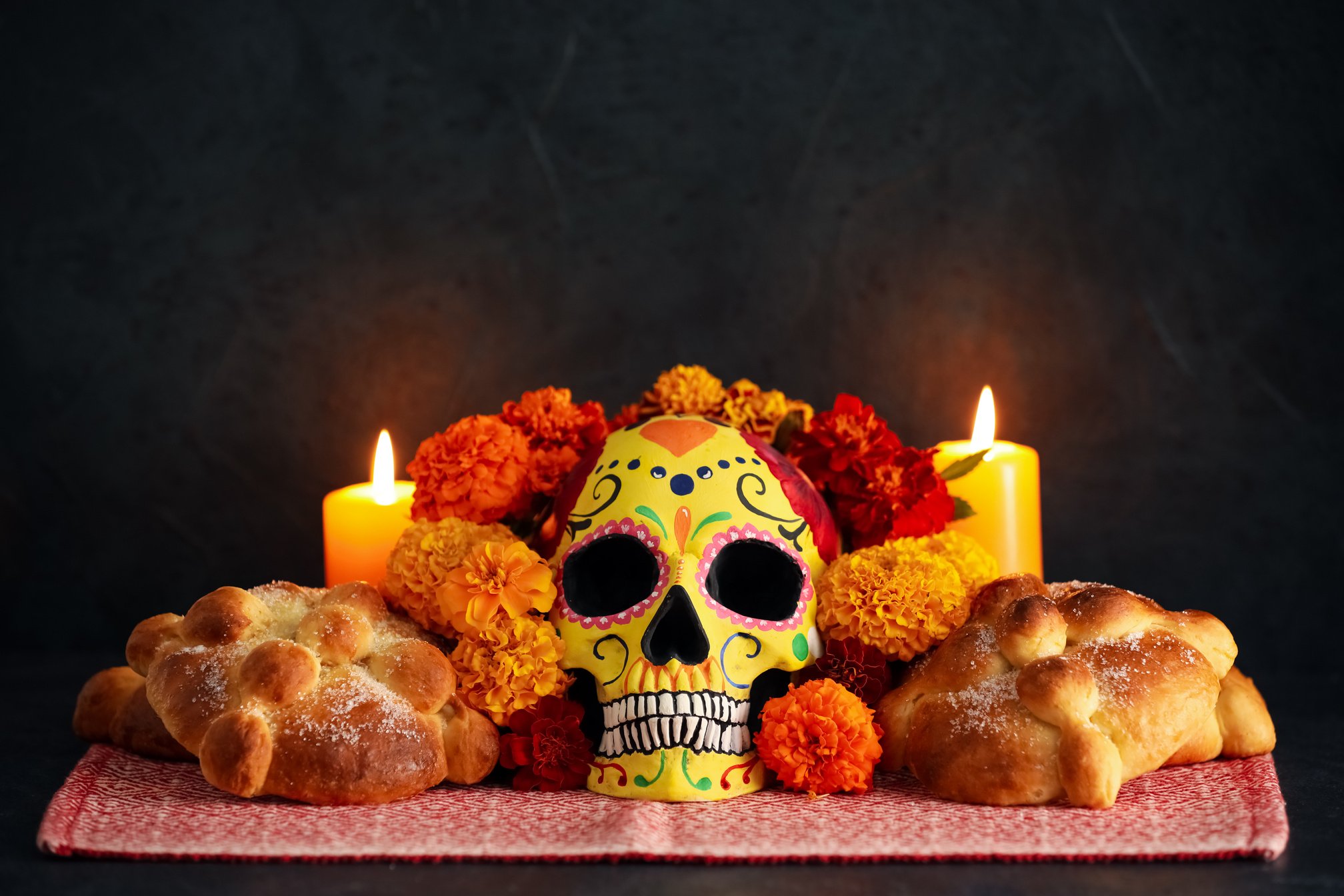 Bread of the Dead and Painted Skull with Marigold Flowers on Dark Background. Celebration of Mexico's Day of the Dead (El Dia De Muertos)